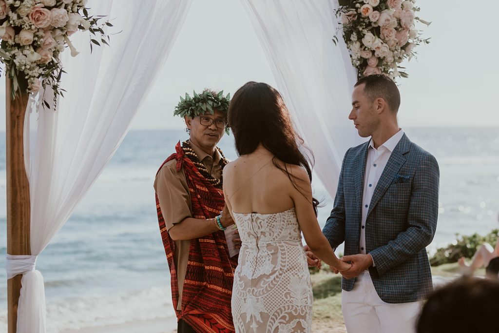 Bride and Groom holding hands and listening to officiant for outdoor beach Ceremony