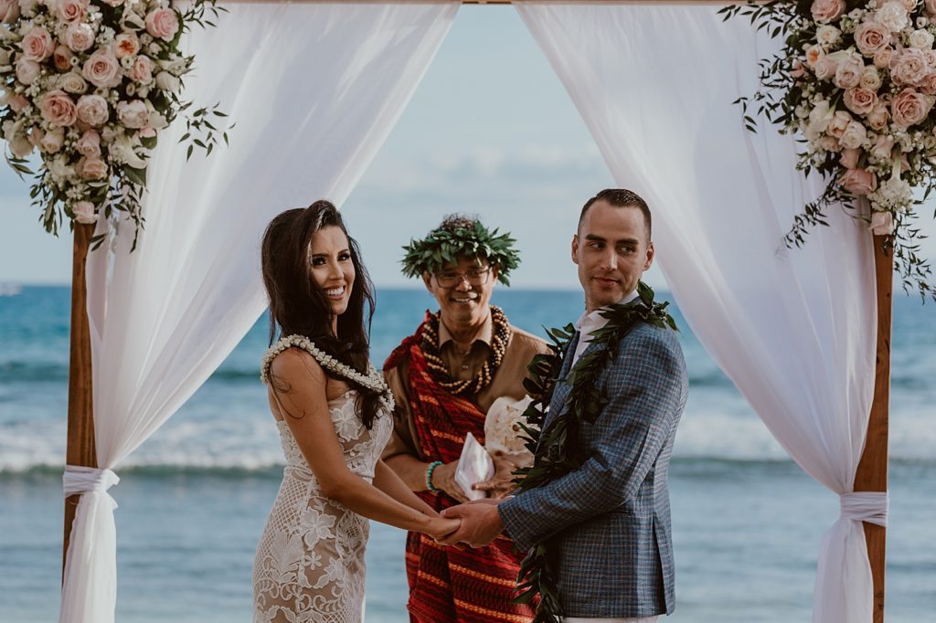 Bride and Groom holding hands at the alter and looking at the audience