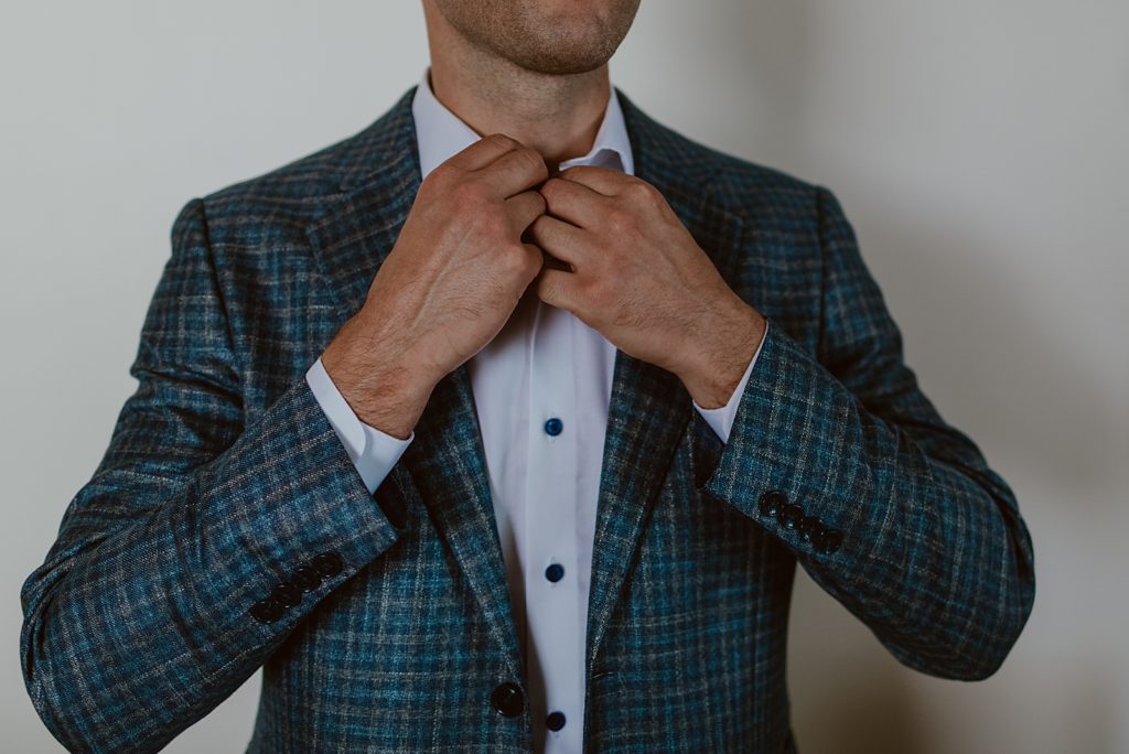 Closeup of Groom buttoning shirt