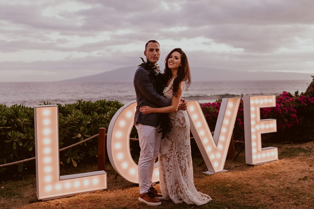 Bride and Groom hugging in front of "LOVE" sign