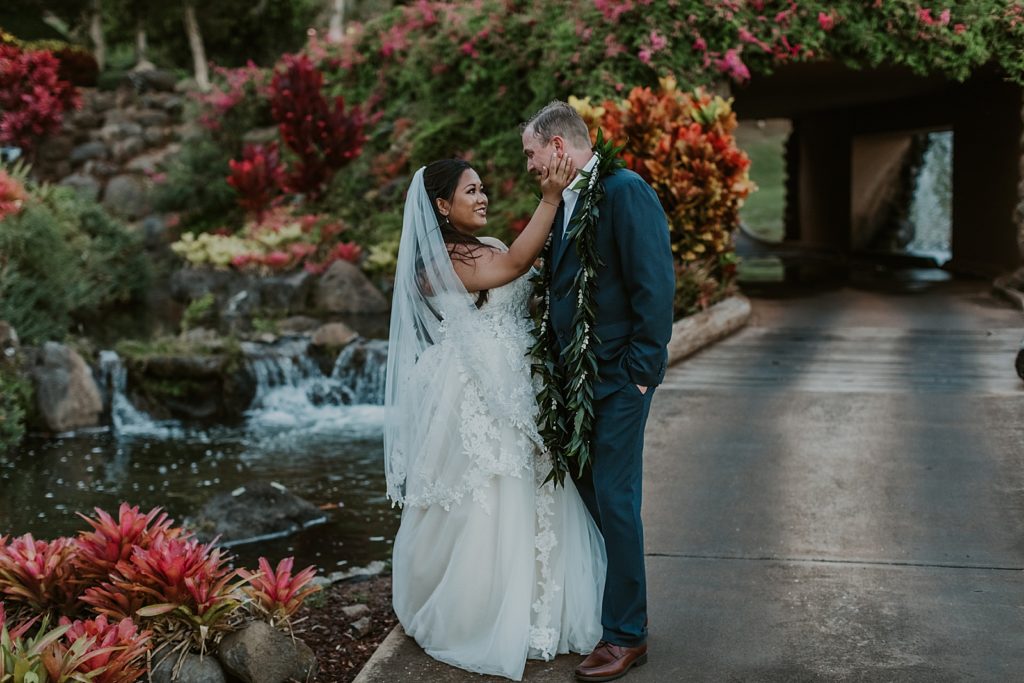 Bride holding Groom's face by koi pond