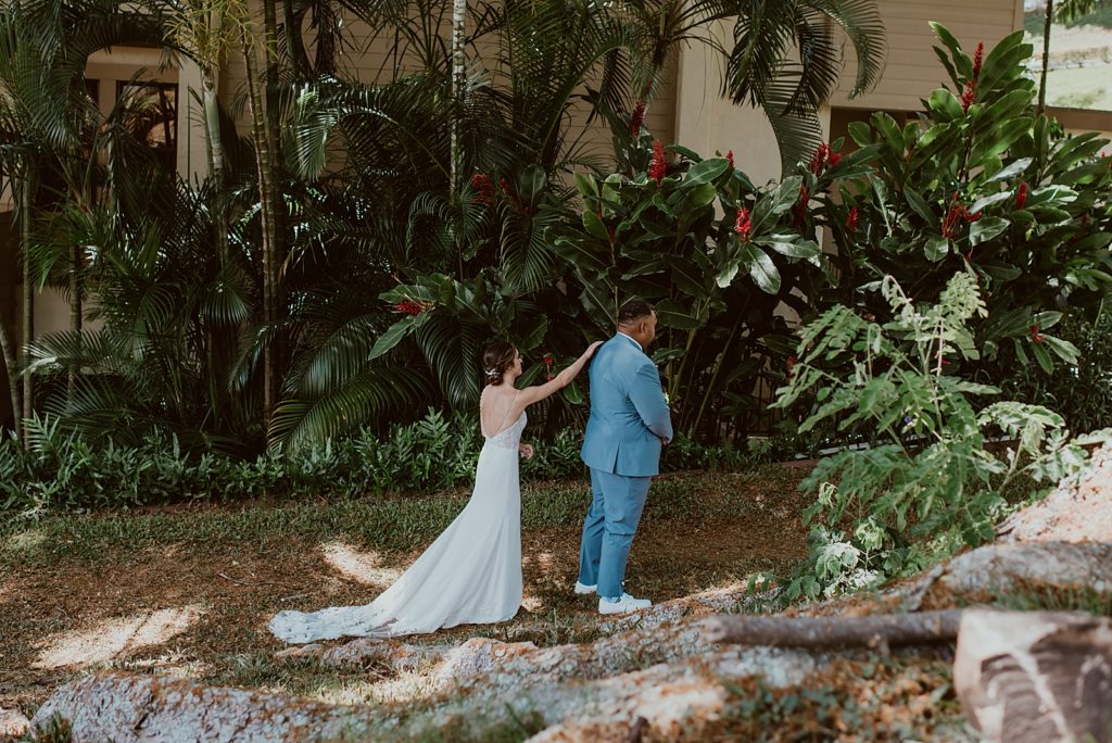 Bride tapping Groom's shoulder for First Look in green plant area