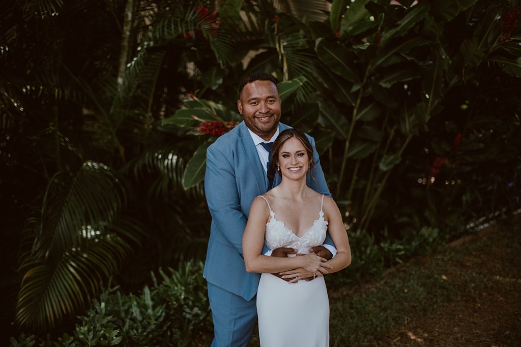 Portrait of Groom holding Bride in luscious green area