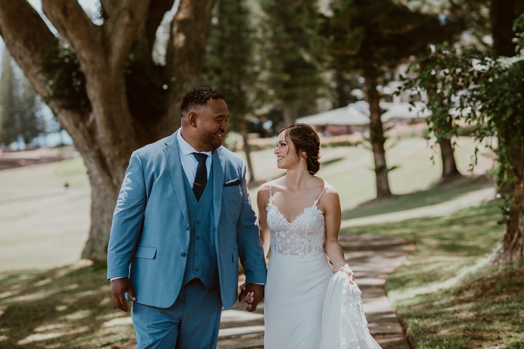 Bride and Groom holding hands looking at each other as they walk on the sidewalk