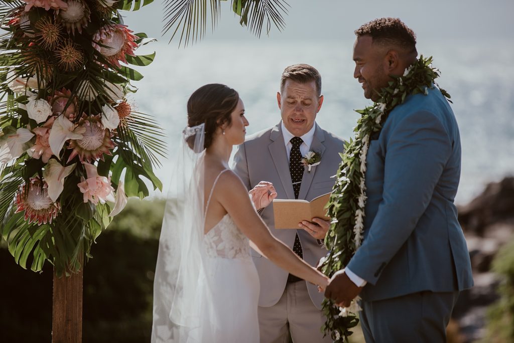 Bride and Groom holding hands and looking at each other during Homily for Ceremony