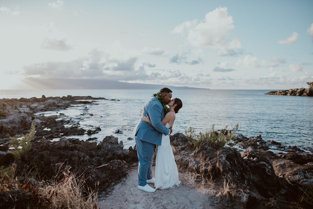 Bride and Groom holding each other and kissing by the water