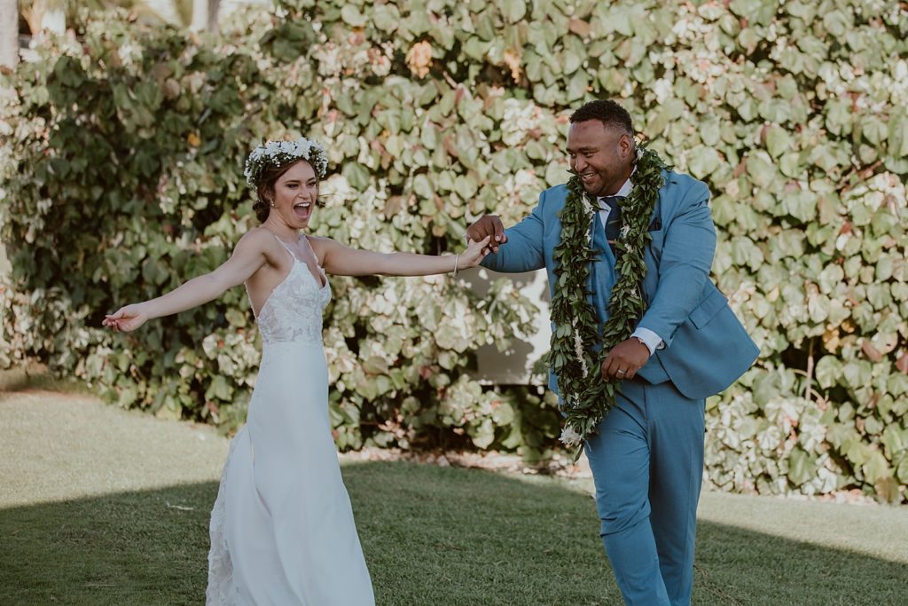 Bride and Groom holding hands and dancing on the grass