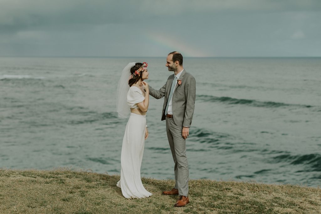 Groom with hand on Bride in front of water