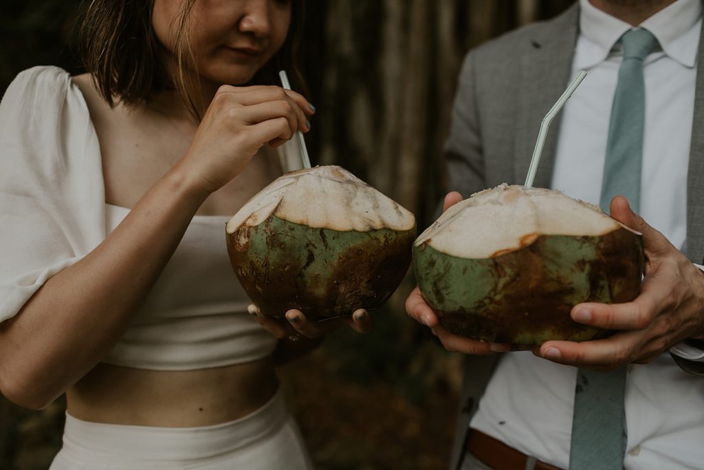 Closeup of Bride and Groom holding coconuts with straws in them