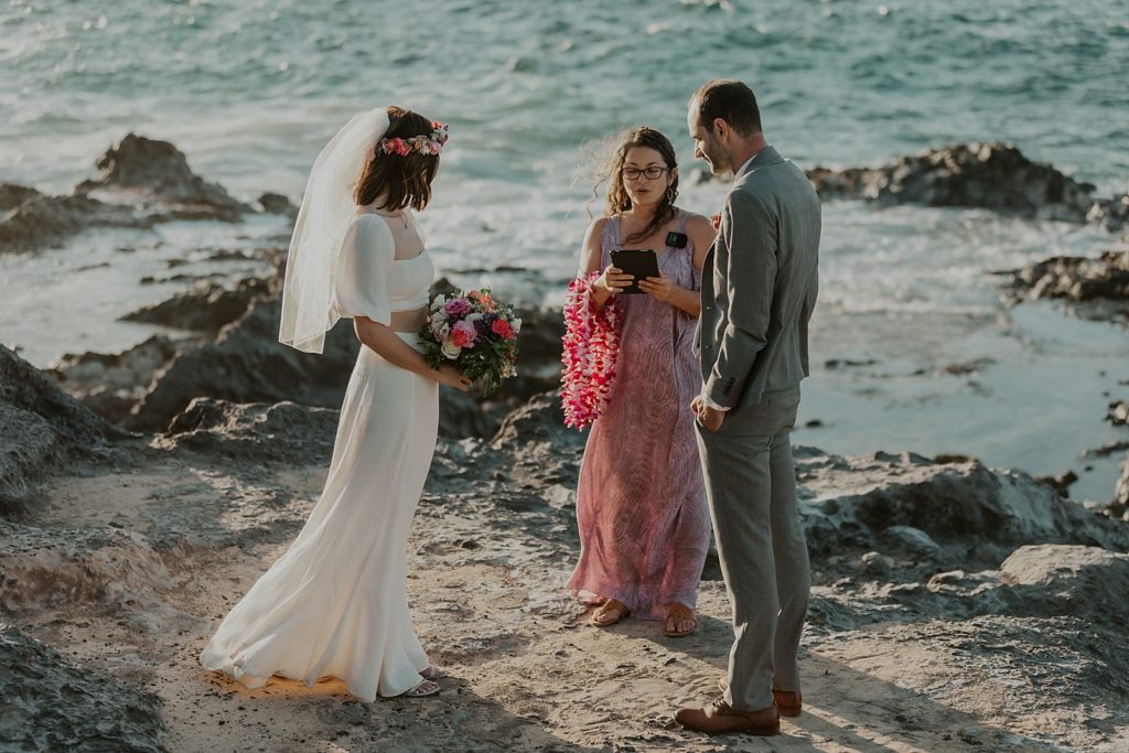 Bride and Groom listening to officiant by the rocky shoreline for Ceremony