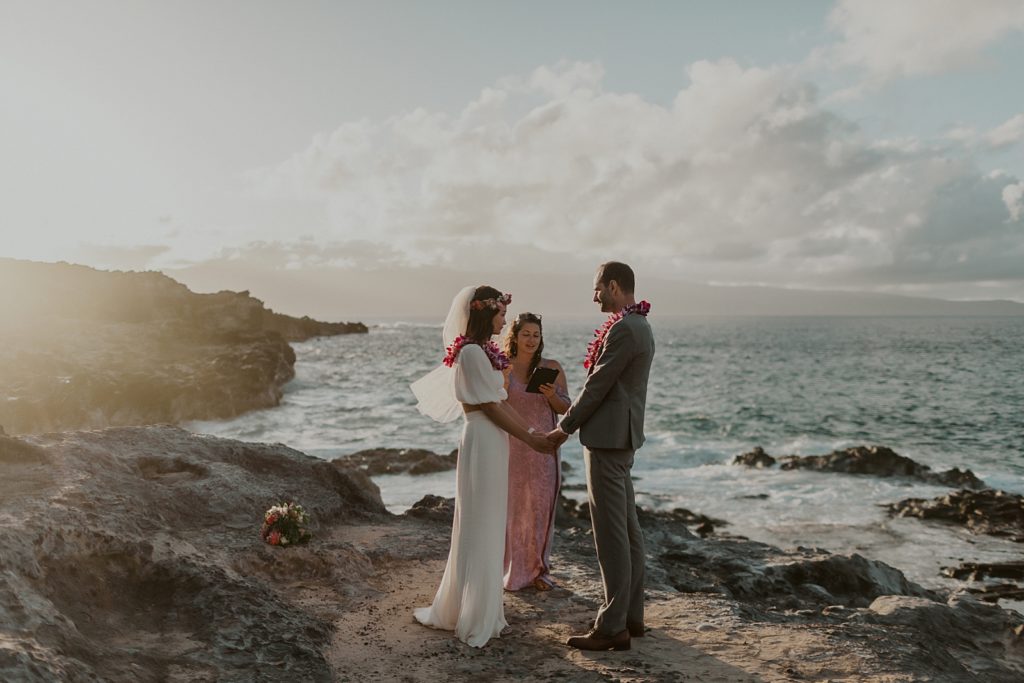 Bride and Groom hand in hand during Ceremony in front of ocean