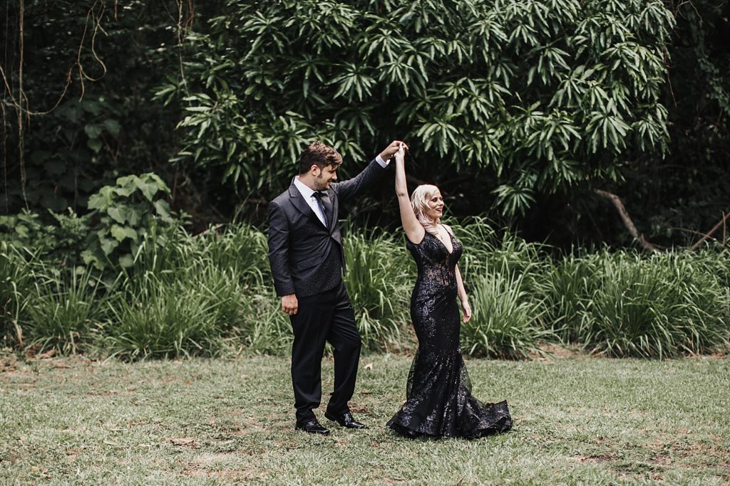 Bride twirling by Groom's hand on green field
