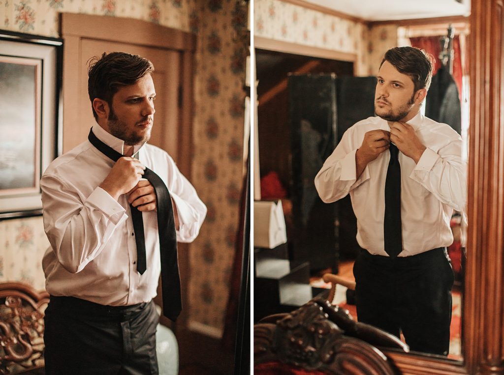 Groom getting ready tying tie in the mirror