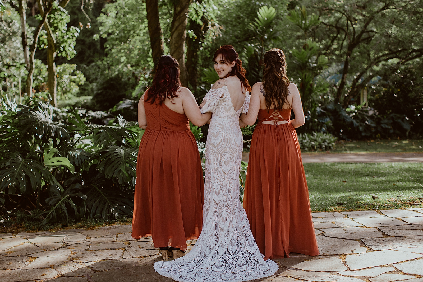 Bride looking behind arm in arm with Bridesmaids