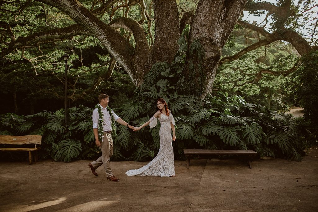 Bride holding Groom's hand leading him on path