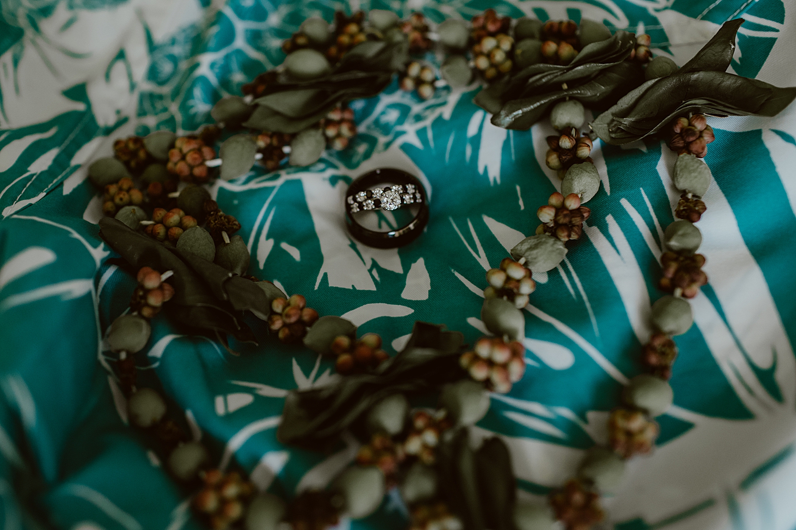 Detail shot of wedding bands and engagement ring on tropical clothes