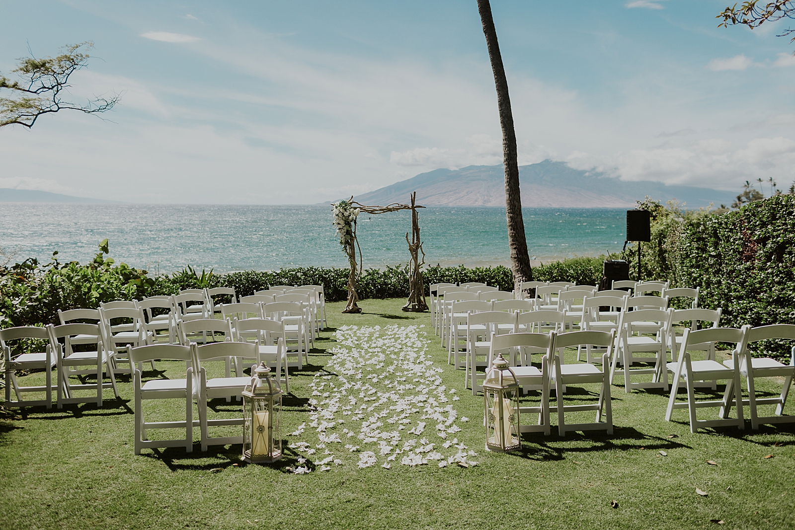 Detail shot of outdoor Ceremony area with flower runner and wood arch and water