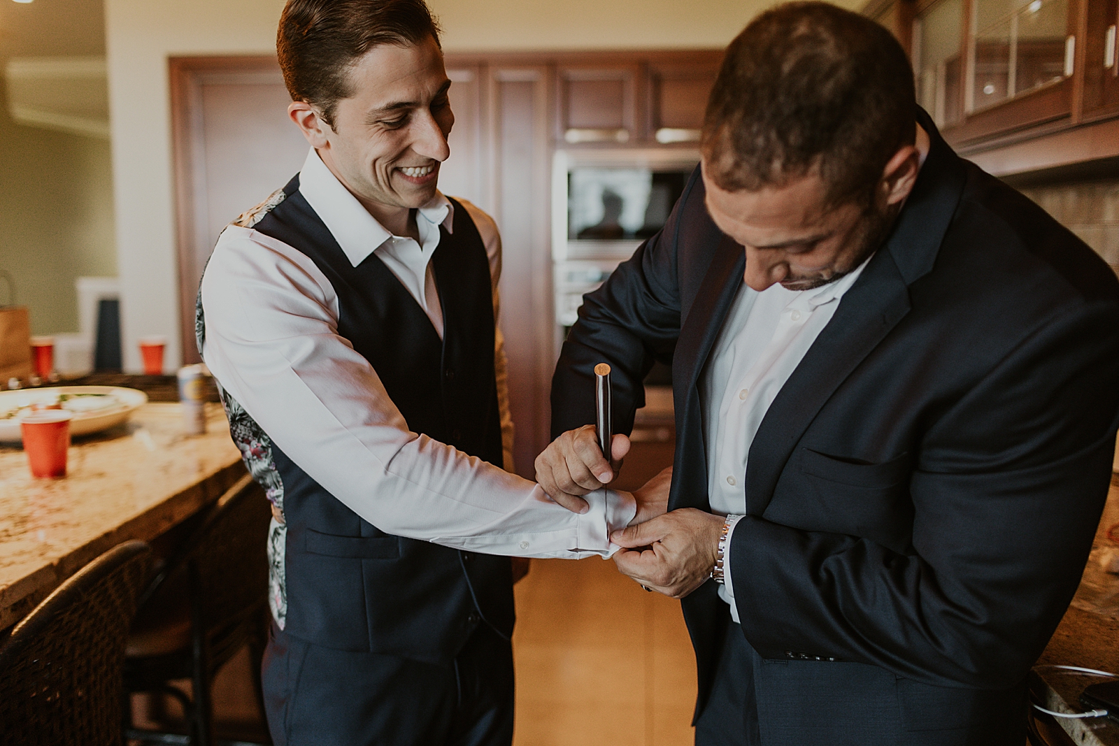 Groom getting help with cuff getting ready