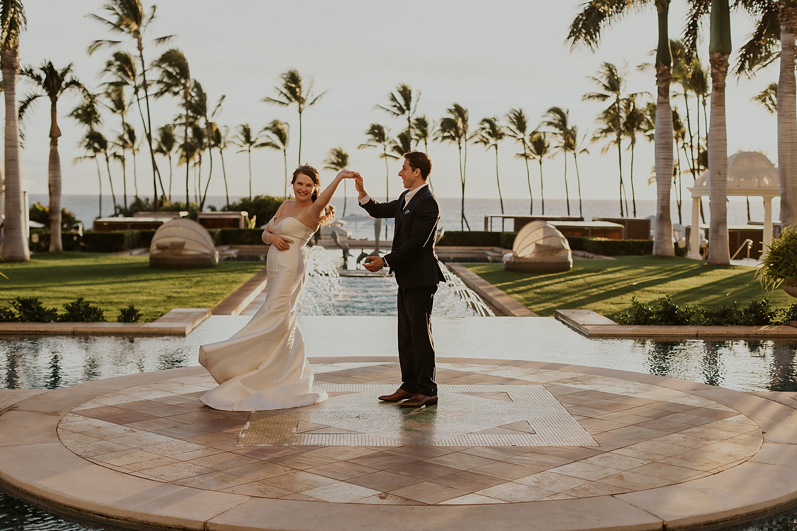Bride twirling by Groom's hand in center of water fountain area