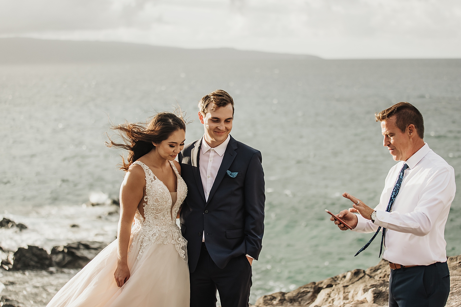 Bride and Groom listening to Officiant for cliffside ocean Elopement