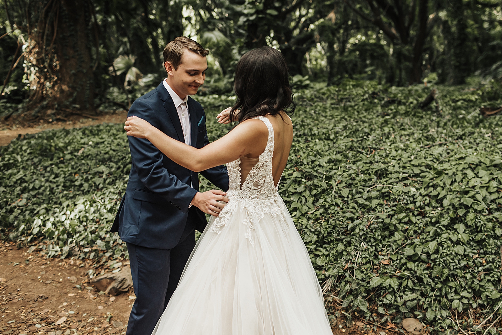 Bride and Groom leaning in to hug each other by greenery
