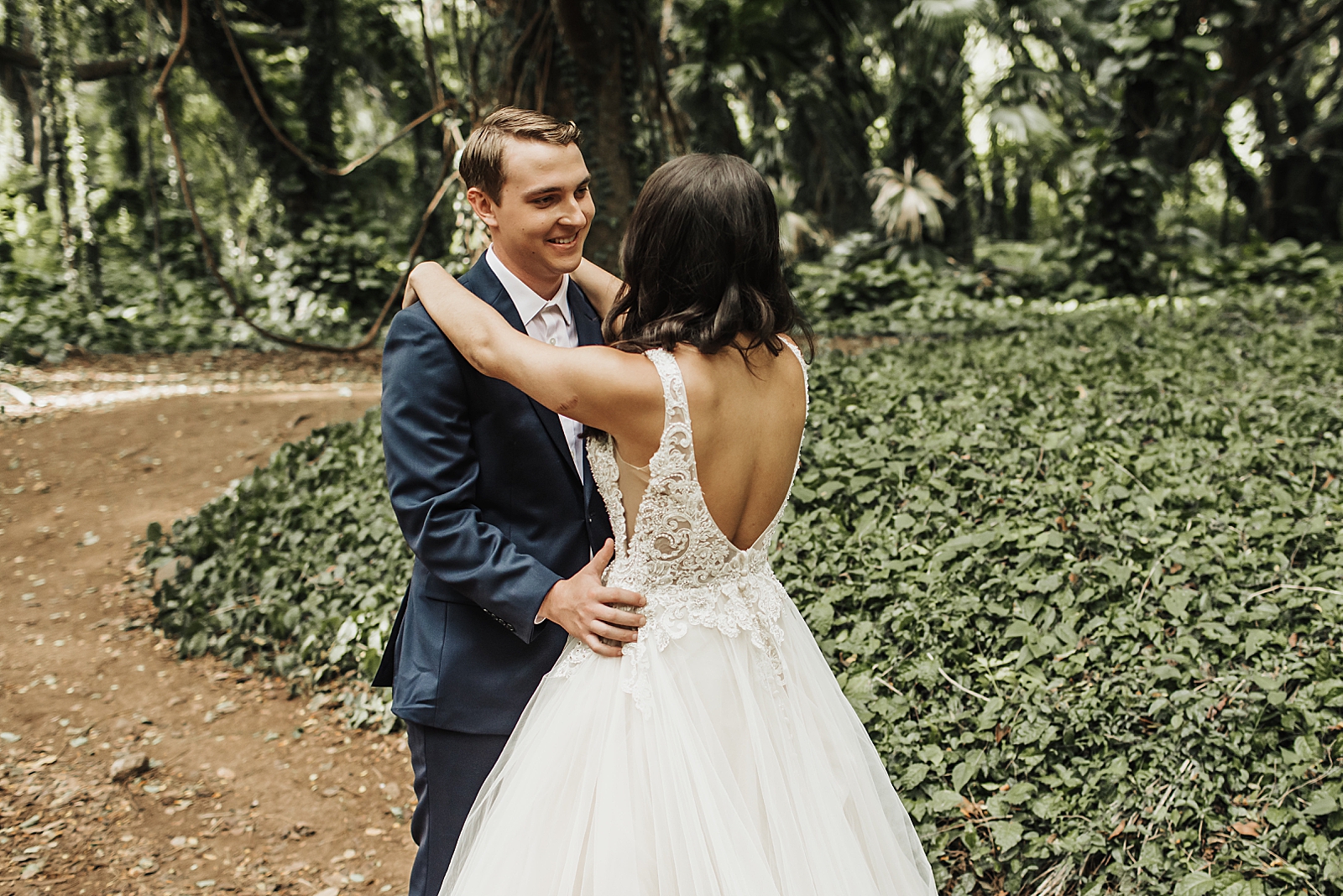 Bride and Groom holding each other by greenery
