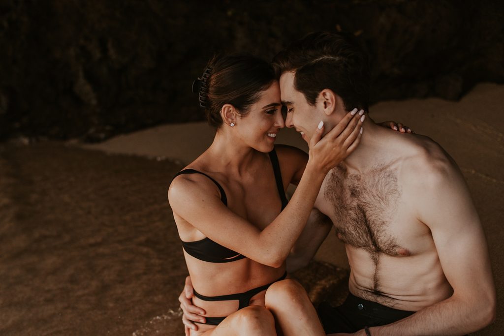 Couple sitting together under beach sand cove and resting their heads on each other