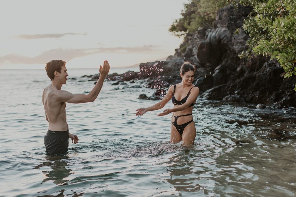 Man splashing water on woman in knee deep water