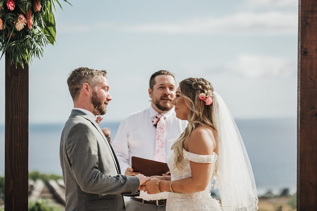 Bride and Groom holding hands with officiant giving homily