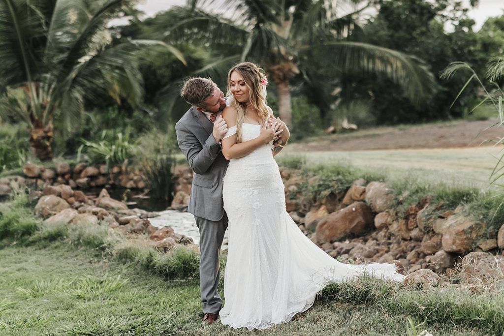 Groom holding Bride from behind and looking into her eyes outside