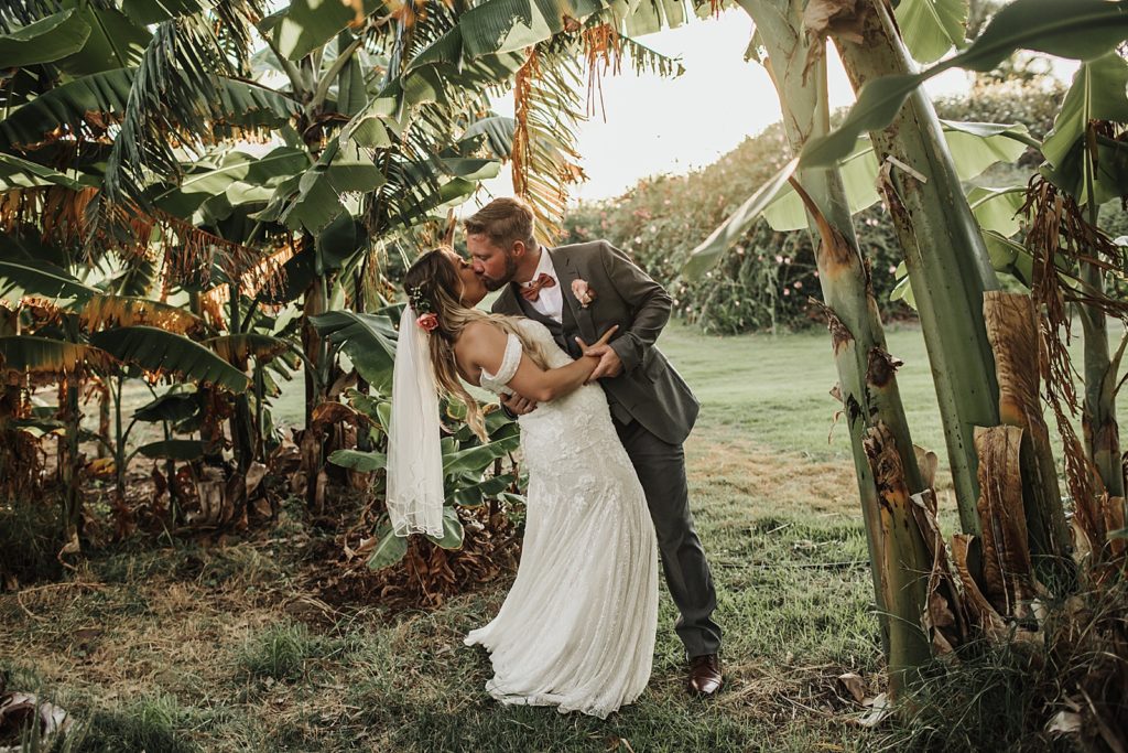 Bride and Groom dipping and kissing by greenery
