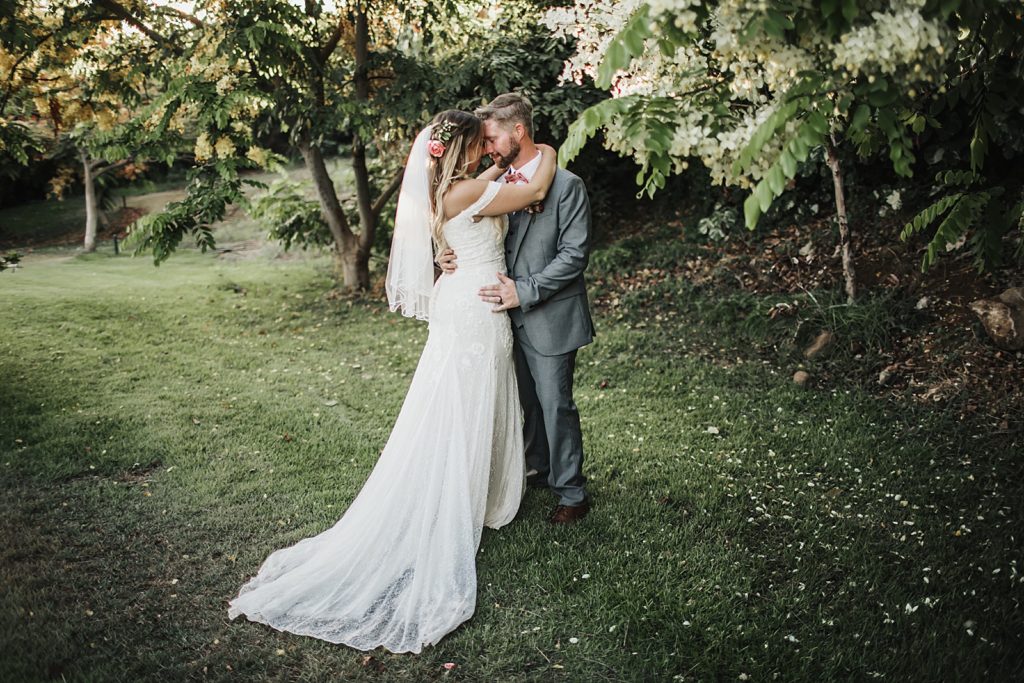 Bride and Groom holding each other and resting each other by greenery