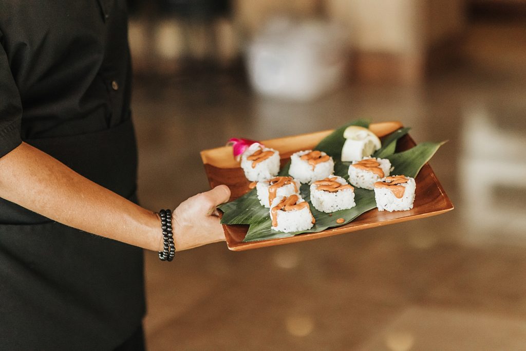 Detail closeup shot of sushi rolls topped with sauce with platter