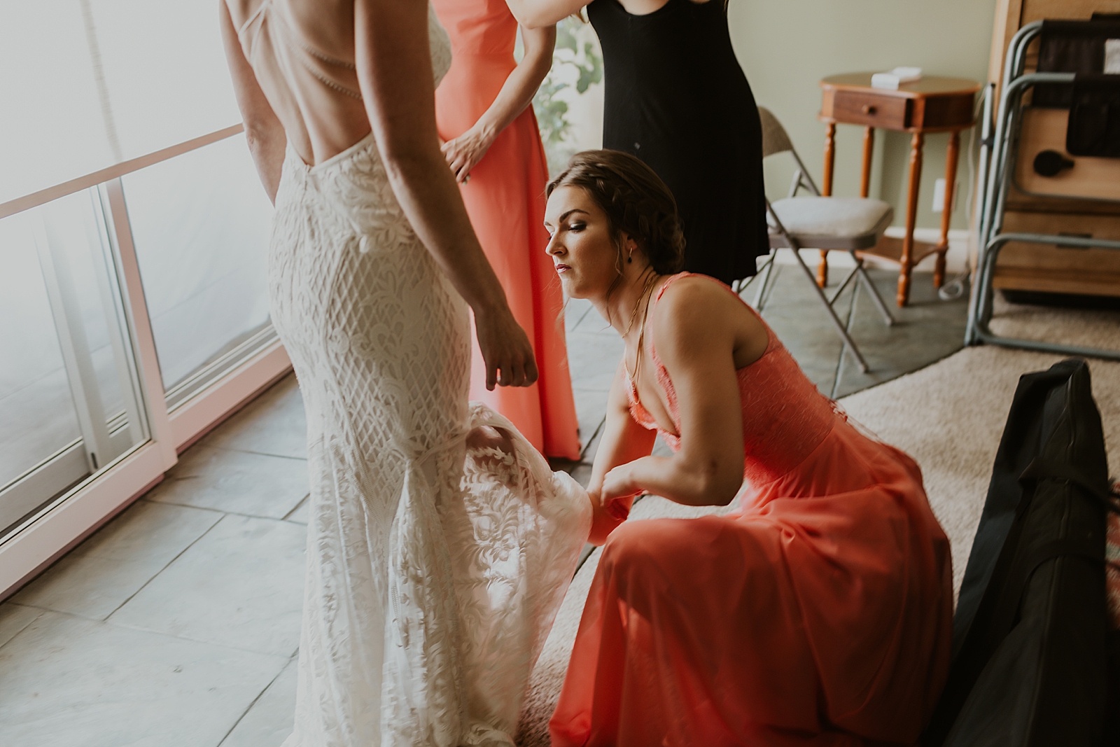 Bridesmaids helping get wedding dress on Bride