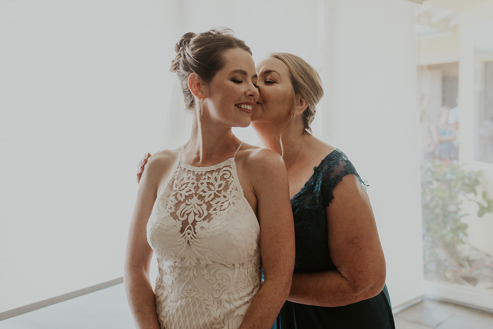 Mother kissing Bride on cheek after helping get her ready