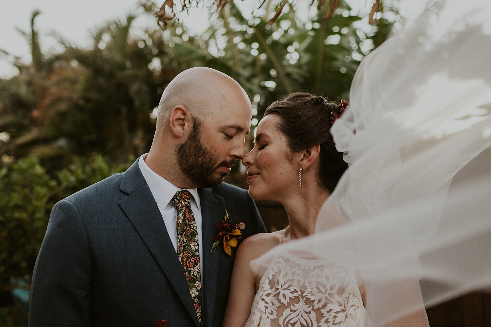Bride and Groom touching noses with veil flowing in the air