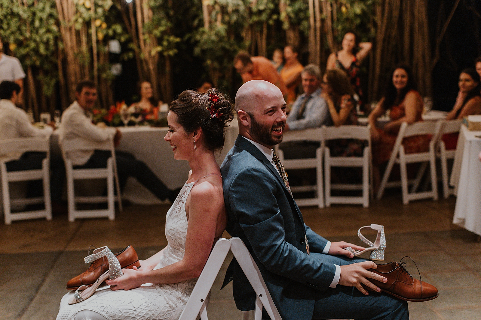 Bride and Groom sitting back to back for wedding game with shoes for Reception