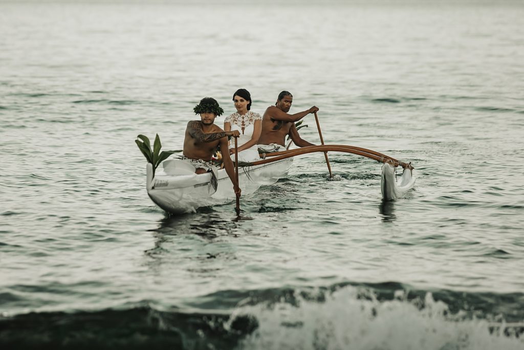 Bride coming to shore with paddlers bringing boat to shore