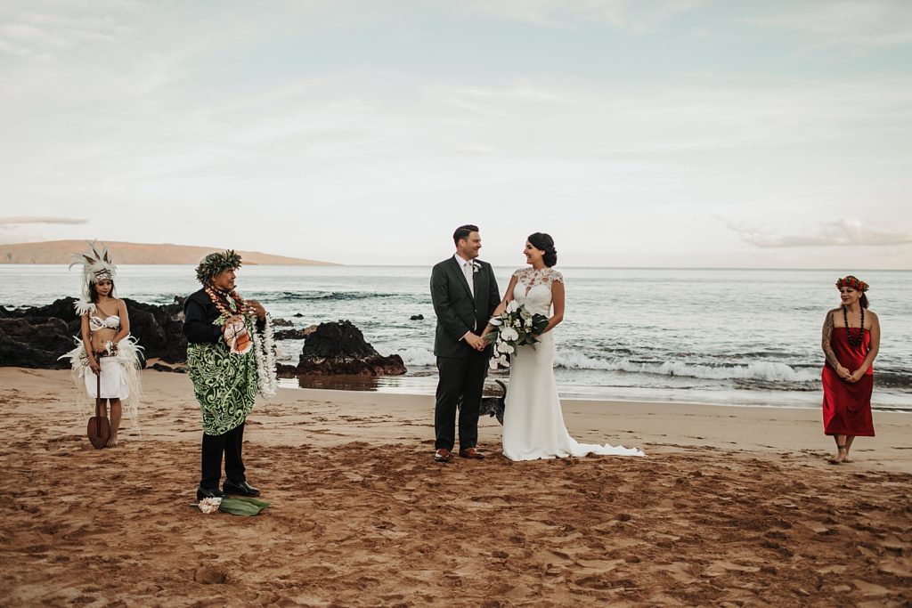 Bride and Groom holding hands looking at each other on the beach