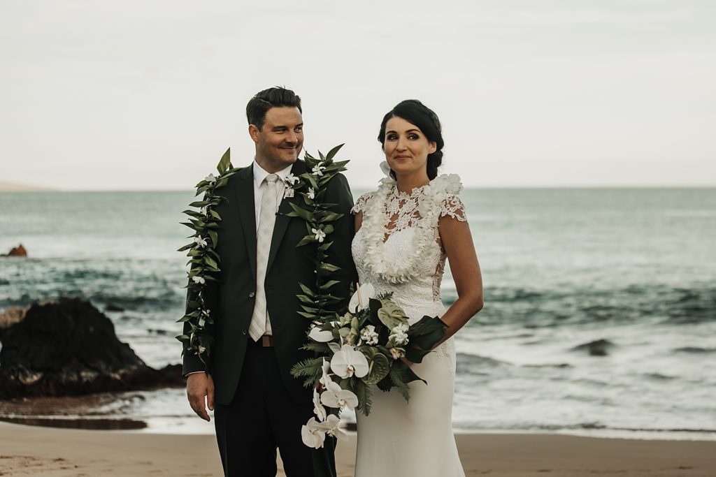 Bride and Groom holding hands on the beach by the ocean