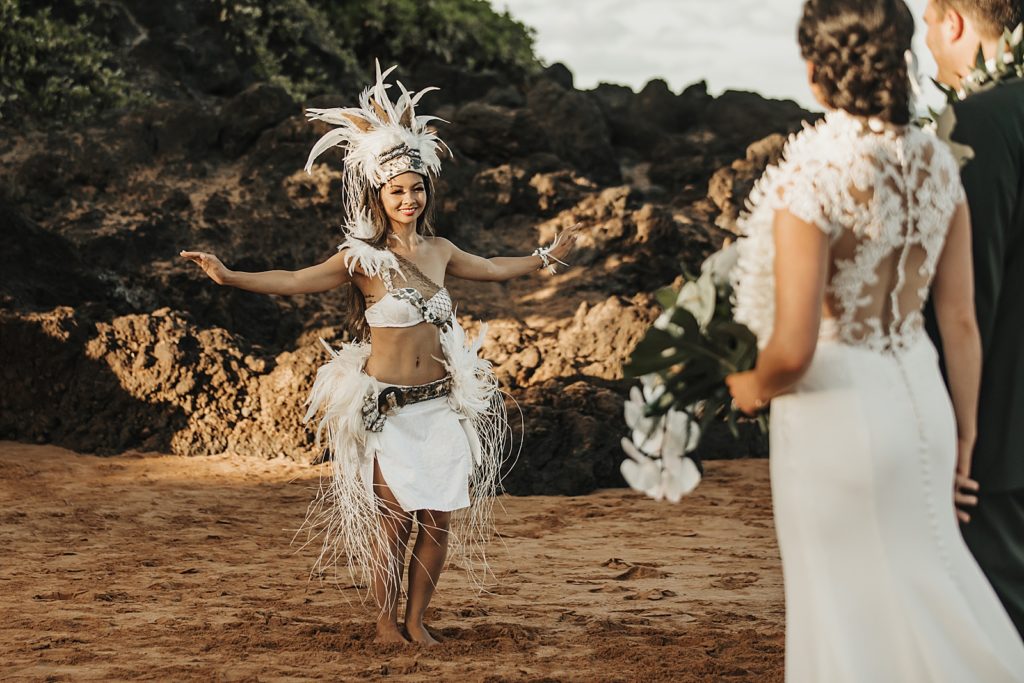 Bride and Groom watching Ceremony dancer with white Hawaiian outfit on sand