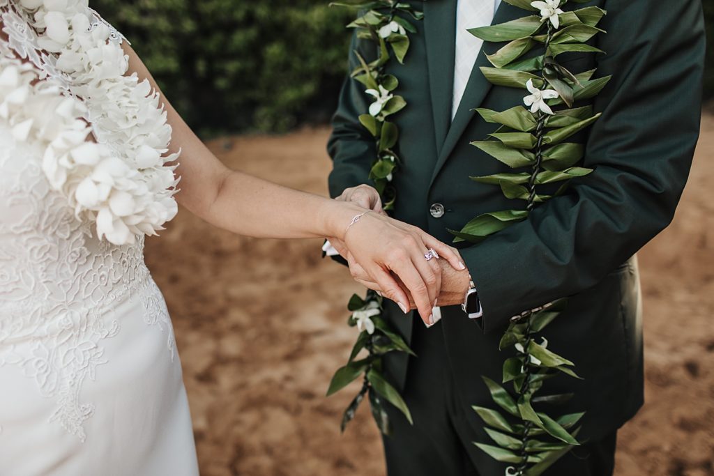 Groom holding Bride's hand while they are on the beach