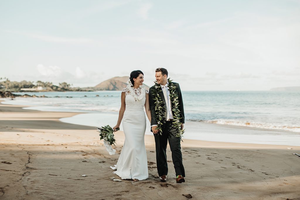 Bride and Groom holding hands and walking on the beach together