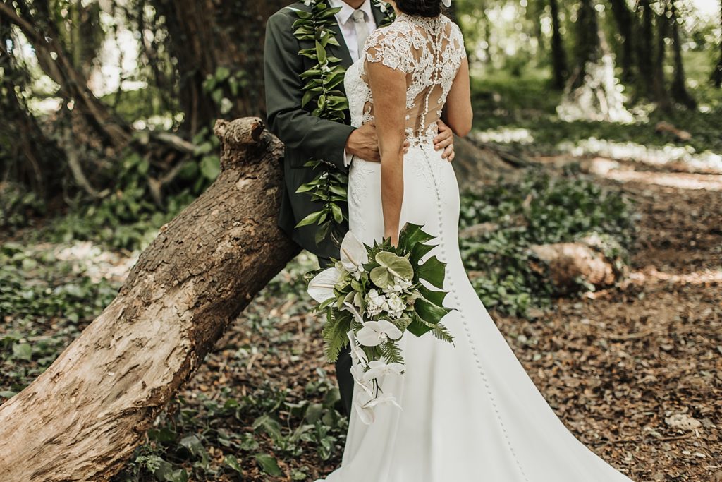 Closeup of Bride and Groom hugging while sitting on fallen tree trunk in the forest