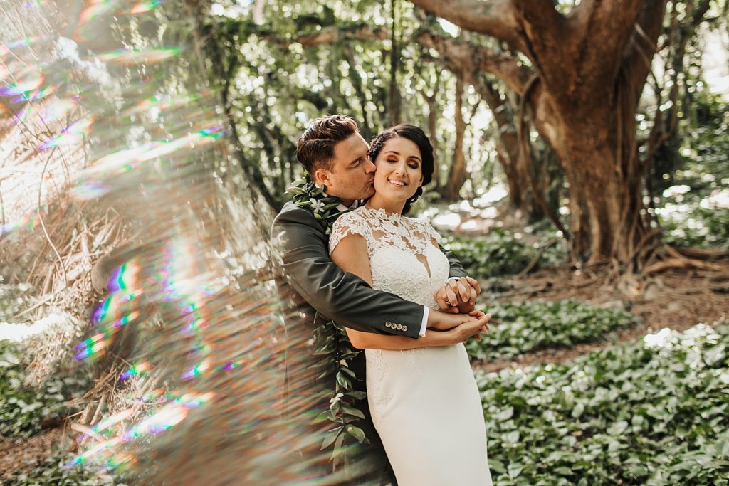 Groom holding Bride from behind in the forest with greenery