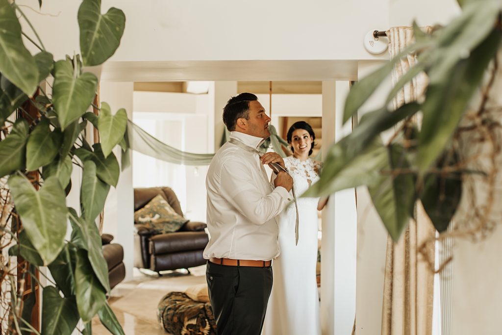 Groom adjusting tie inside with Bride next to him