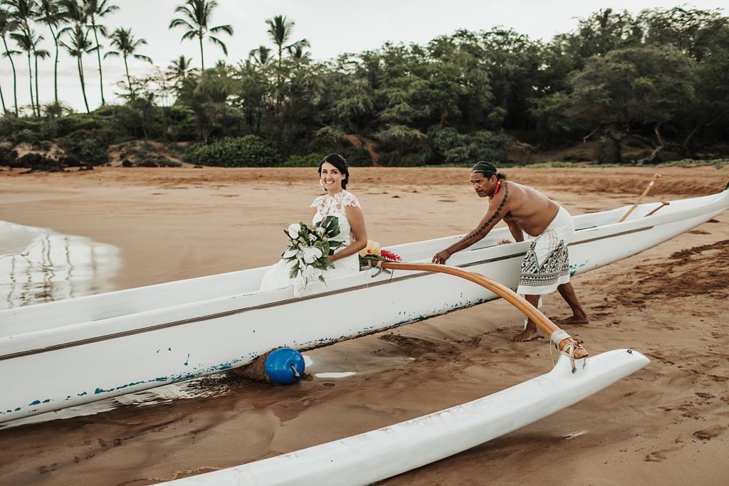 Bride in Hawaiian boat being pushed out by professional sailor