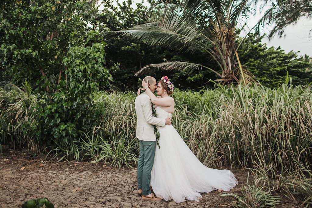 Bride and Groom holding each other by greenery