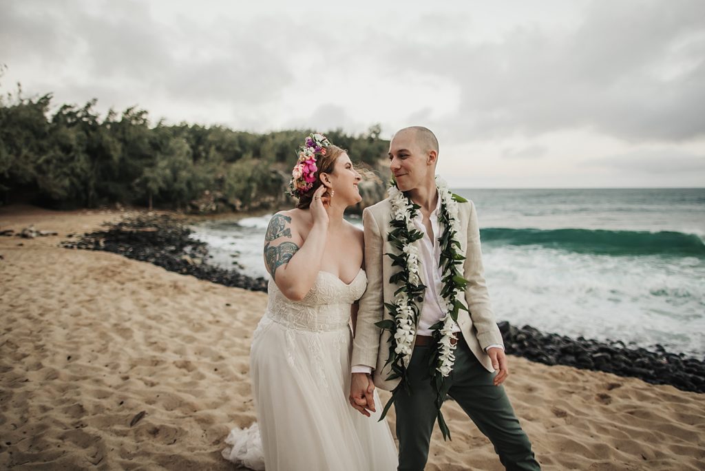 Bride and Groom holding hands and walking on the sand together by the ocean