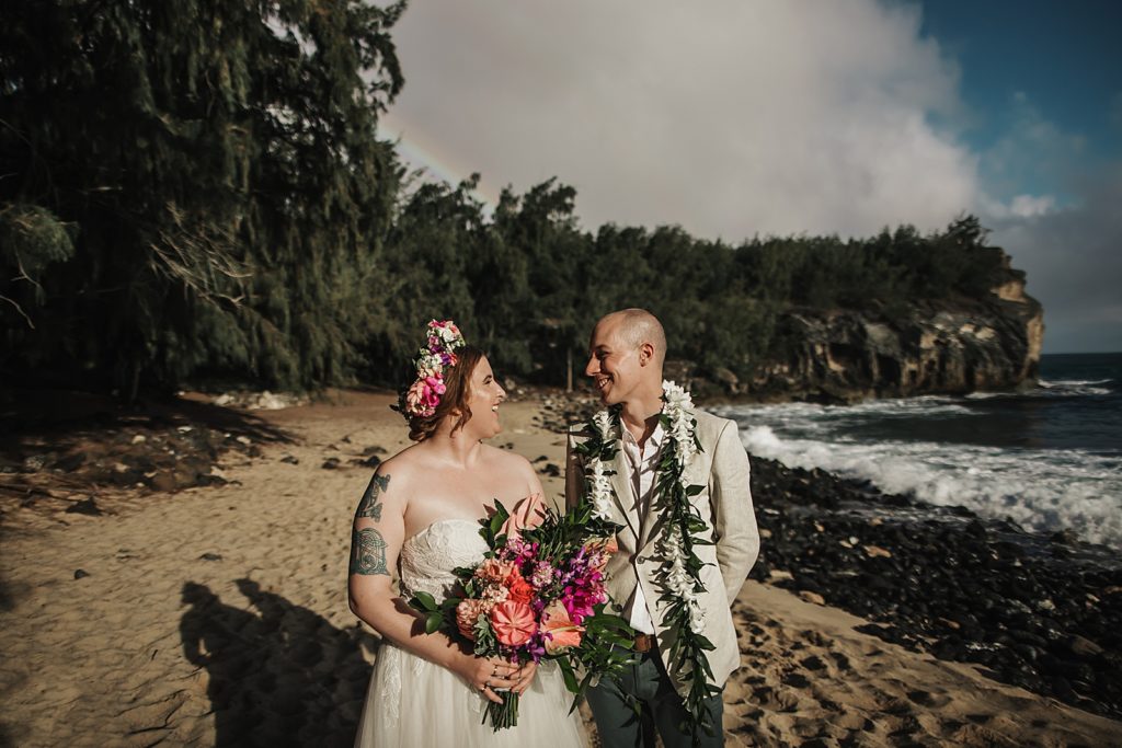 Bride and Groom looking at each other on the beach by the water